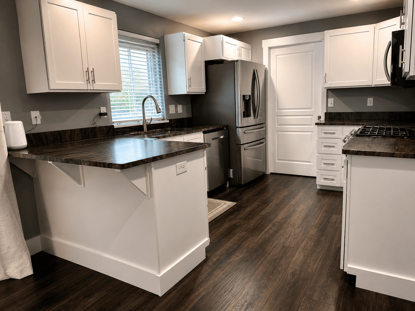 Modern kitchen with white cabinets, dark wood countertops, stainless steel appliances, and dark wood flooring.